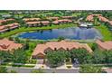 Stunning aerial view of community featuring a serene lake, pool, lush greenery, and well-maintained townhome exteriors at 10308 Belfry Cir, Orlando, FL 32832