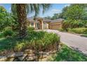 Inviting home featuring a brick driveway, two-car garage, lush landscaping, and an arched entryway at 140 Seville Chase Dr, Winter Springs, FL 32708