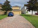 Paver driveway leading to a yellow two-car garage at 15208 Avenue Of The Arbors, Winter Garden, FL 34787