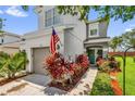 Charming townhome with a teal door, a one-car garage, and beautifully landscaped yard with an American flag at 1784 Fritwell Ct, Ocoee, FL 34761