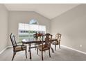Bright dining room with a large window, vaulted ceilings and a wooden table set for four at 3926 Ventura Place, Orlando, FL 32822