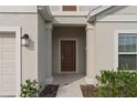 Inviting entryway featuring a solid front door, decorative sidelight, and manicured landscaping at 4223 Little Owl Ln, Kissimmee, FL 34746
