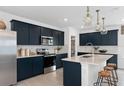 Modern kitchen with stainless steel appliances, dark blue cabinetry, quartz countertops, and stylish pendant lighting at 5021 Starling Bird Ln, St Cloud, FL 34771