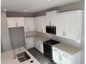 Bright kitchen featuring quartz countertops, white cabinets, and modern stainless steel appliances at 551 Pothos St, Apopka, FL 32703