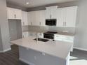Modern kitchen with island, quartz countertops, stainless appliances, and white cabinetry at 551 Pothos St, Apopka, FL 32703