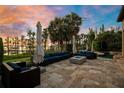 Elegant outdoor patio with travertine floors, comfortable seating, umbrellas and lake views at 11103 Bridge House Rd, Windermere, FL 34786