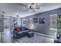 Cozy living room with a blue sofa, gray rug, ceiling fan, and natural light from windows, perfect for relaxation at 114 Vista Verdi Cir # 116, Lake Mary, FL 32746