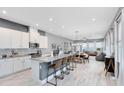 Open-concept kitchen with white cabinets, granite countertops, island seating, and modern appliances at 13334 Beebe Aly, Orlando, FL 32827