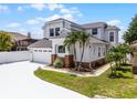 Two story home featuring an attached two car garage, neutral paint, decorative brick detail, and tropical landscaping at 14423 Tambourine Dr, Orlando, FL 32837