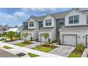 View of the townhomes with modern farmhouse design, white siding, garages, and tidy landscaping at 1462 Brookdale Ct, Oviedo, FL 32765