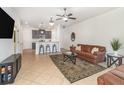Open-concept living area with breakfast bar, neutral paint, tile flooring, ceiling fan, and television at 178 Windflower Way, Oviedo, FL 32765