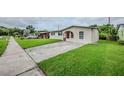 Inviting single-story house boasts a well-manicured lawn, long driveway, and neutral exterior paint at 26 Channing Ave, Orlando, FL 32811