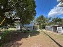 Backyard view of home showcasing spacious lawn, storage building, and mature shade trees at 2847 Cr 756, Webster, FL 33597