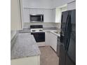 Updated kitchen with white cabinets, granite countertops and modern black appliances at 3305 Robinson St, Zellwood, FL 32798