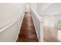 Elegant staircase featuring hardwood steps, white banisters, and an open view of the living area at 442 Churchill Ct, Kissimmee, FL 34759