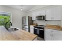 Bright kitchen featuring stainless steel appliances, light wood countertops, and white cabinets at 103 Gleason Cv, Sanford, FL 32773