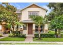 Inviting two-story home featuring a front porch, lush landscaping, and a charming brick walkway at 14474 Prunningwood Pl, Winter Garden, FL 34787