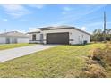 Home exterior with a long driveway leading to a brown two car garage and well maintained lawn at 16730 Sw 50Th Cir, Ocala, FL 34473