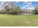 Single-story home with a wraparound porch and expansive green lawn surrounded by mature trees at 2691 Phillips Rd, Christmas, FL 32709