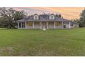 Inviting single-story home at sunset with a wraparound porch and expansive green lawn at 2691 Phillips Rd, Christmas, FL 32709