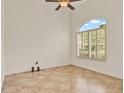 Bright room with neutral-toned tile, ceiling fan, and arched window with plantation shutters at 289 Laurenburg Ln, Ocoee, FL 34761