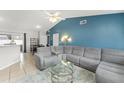 Spacious living room with a gray sectional, a glass coffee table, and open access to the dining area at 3232 Butterfield St, Deltona, FL 32738