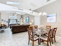 Open-concept dining area with a modern chandelier, tile floors, and a view into the living room at 512 Viola Dr, Davenport, FL 33837
