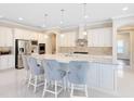 Bright kitchen with white cabinets, stainless steel appliances, granite countertops and four bar stools at 8480 Adalina Pl, Orlando, FL 32827