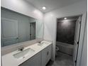 Bright bathroom features a double vanity and an adjoining shower with gray tile at 930 Cattleman St, Winter Haven, FL 33881