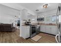 Efficient kitchen with white cabinetry, stainless steel appliances, and hardwood flooring, with a view to the living room at 1328 Vassar St, Orlando, FL 32804