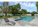 Beautiful backyard pool with a sun shelf and spillover spa, surrounded by lush landscaping and an enclosed fence at 1328 Vassar St, Orlando, FL 32804