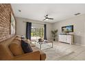 Inviting living room featuring a decorative brick wall, plush sofa, and a sliding glass door leading to the backyard at 14016 Fox Glove St, Winter Garden, FL 34787