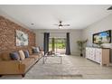 Inviting living room featuring a decorative brick wall, plush sofa, and a sliding glass door leading to the backyard at 14016 Fox Glove St, Winter Garden, FL 34787