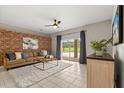 Inviting living room featuring a decorative brick wall, plush sofa, and a sliding glass door leading to the backyard at 14016 Fox Glove St, Winter Garden, FL 34787