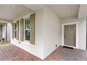 Inviting front porch with decorative brick flooring, and paneled front door, and windows with brown shutters at 16013 Tollington Aly, Winter Garden, FL 34787