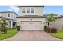 A two-car garage showing the driveway and the front of the home in a residential neighborhood with a landscaped lawn at 16013 Tollington Aly, Winter Garden, FL 34787