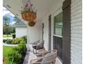 Inviting front porch with decorative hanging plants, wicker chairs, and a brick facade at 207 Ramsbury Ct, Longwood, FL 32779