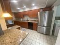 Galley kitchen with stainless steel fridge, granite countertops and wooden cabinets at 2500 21St Nw St # 58, Winter Haven, FL 33881