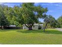 Large tree and manicured lawn surround this house, with a metal roof and hedging at 63 Madera Rd, Debary, FL 32713