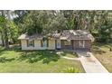 Lovely single-story home featuring a well-manicured lawn and lush landscaping at 881 Cedar Cir, Tavares, FL 32778