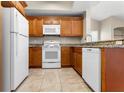 Well-equipped kitchen with white appliances, granite countertops, and warm wood cabinetry at 1101 Vintage Village Ln # 101, Ocoee, FL 34761