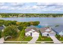Aerial view of home by a lake with a well-maintained lawn, framed by lush greenery and neighborhood at 4642 Waterside Pointe Cir, Orlando, FL 32829