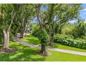 Scenic view of the brick driveway surrounded by mature trees and a well-manicured lawn at 685 Mayo Ave, Maitland, FL 32751