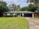 Inviting single-story home with a lush green lawn, mature trees, and a convenient attached two-car garage at 8404 Singapore Ct, Orlando, FL 32817