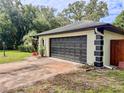 Attached two-car garage with a black door, set against a green lawn and surrounded by mature trees at 8404 Singapore Ct, Orlando, FL 32817