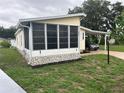 A well-maintained manufactured home featuring a sunny screened-in porch and convenient covered parking at 125 Darlene Ct, Davenport, FL 33897