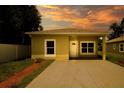 Tan single story home with a modern design, concrete driveway, and a well-maintained, landscaped yard during sunset at 144 Mandrake St, Orlando, FL 32811