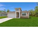 Inviting one-story home featuring a two-car garage, manicured lawn, and decorative stone accents at 16357 Se 88Th Ct, Summerfield, FL 34491