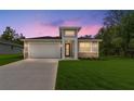 Beautiful twilight view of a cozy single-story home with manicured lawn and stylish exterior lighting at 16357 Se 88Th Ct, Summerfield, FL 34491