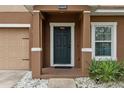 Close up of front porch showing covered area, dark front door, and trimmed landscaping at 1961 Continental St, St Cloud, FL 34769